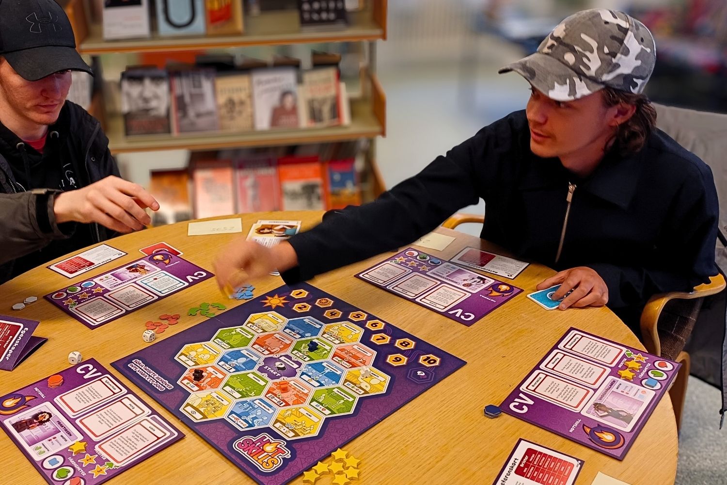 Två unga deltagare spelar brädspelet Hot Skills runt ett bord